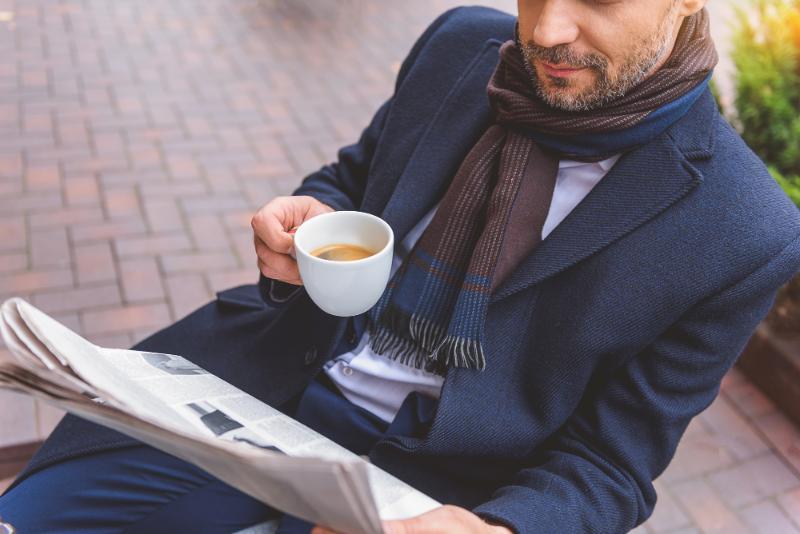 コーヒーを飲みながら新聞を読むビジネスマンの写真